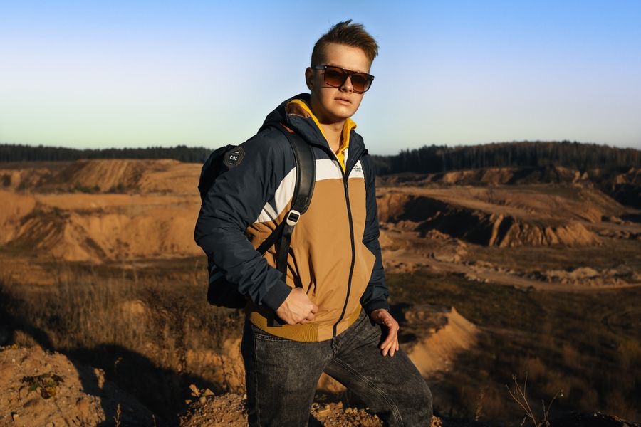 Homme en veste technique ocre avec sac à dos en extérieur