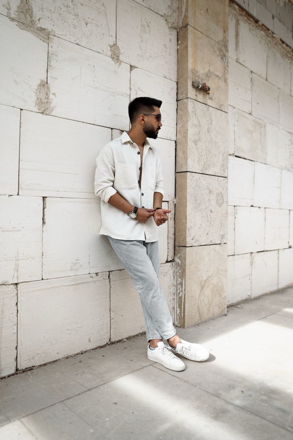 Homme en surchemise écru ouverte sur un t-shirt, pantalon clair