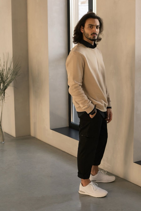Homme en sweat écru et pantalon foncé, sneakers blanches